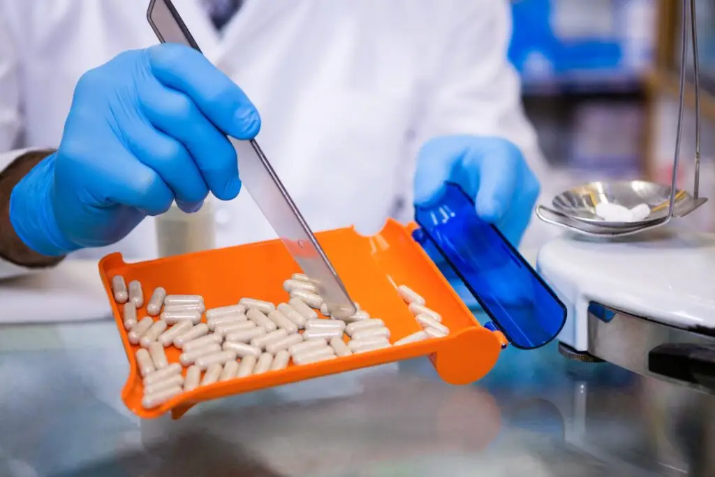 Pharmacist putting pills in container - ADVance Care Pharmacy