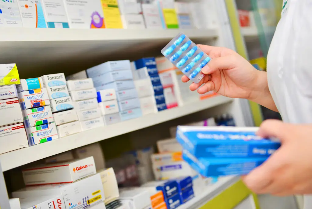 Pharmacist holding medicine box and capsule pack in pharmacy drugstore. - ADVance Care Pharmacy